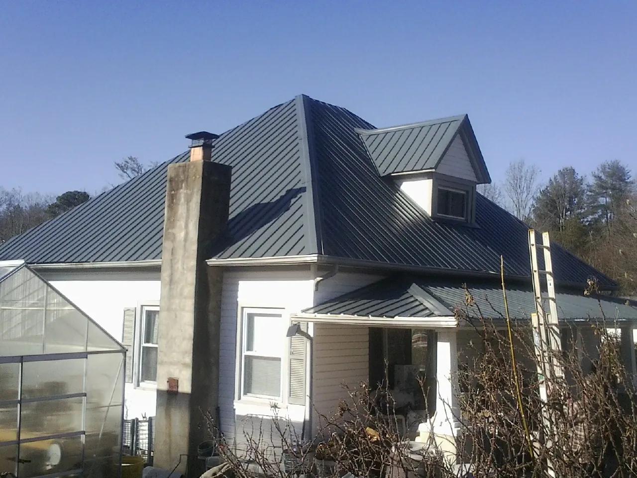 Dark blue standing seam metal roof on a white farmhouse with dormer — Slate & Tile Roof Repair by Roofing Brothers in Conneautville