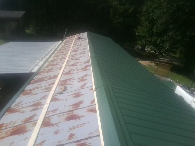 Old rusted panels beside newly installed green metal roofing — Wind Damage Roof Repair by Roofing Brothers in Conneautville