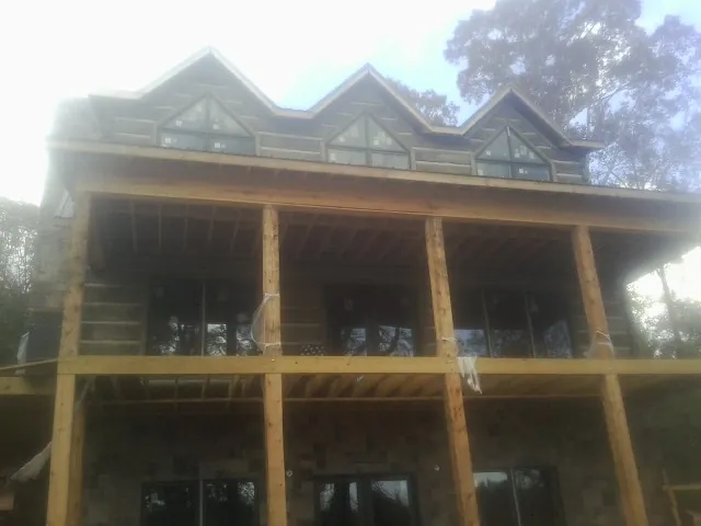 Dormers and porch framing on a large log home under construction — Roof Coating work by our crew in Conneautville