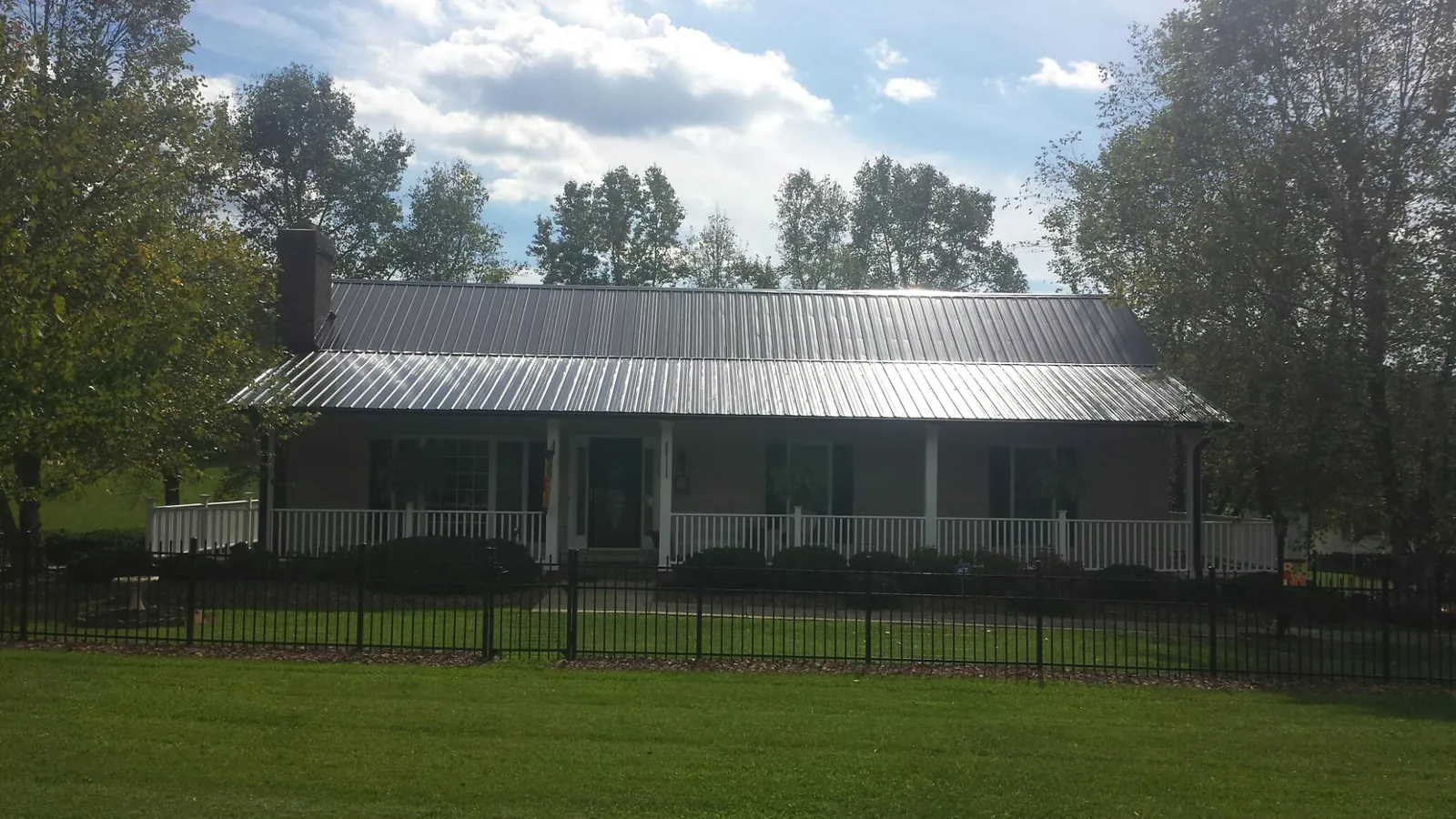 Gray metal roof on a brick ranch with a full width front porch — Gutter Guard Installation work by our crew in Conneautville