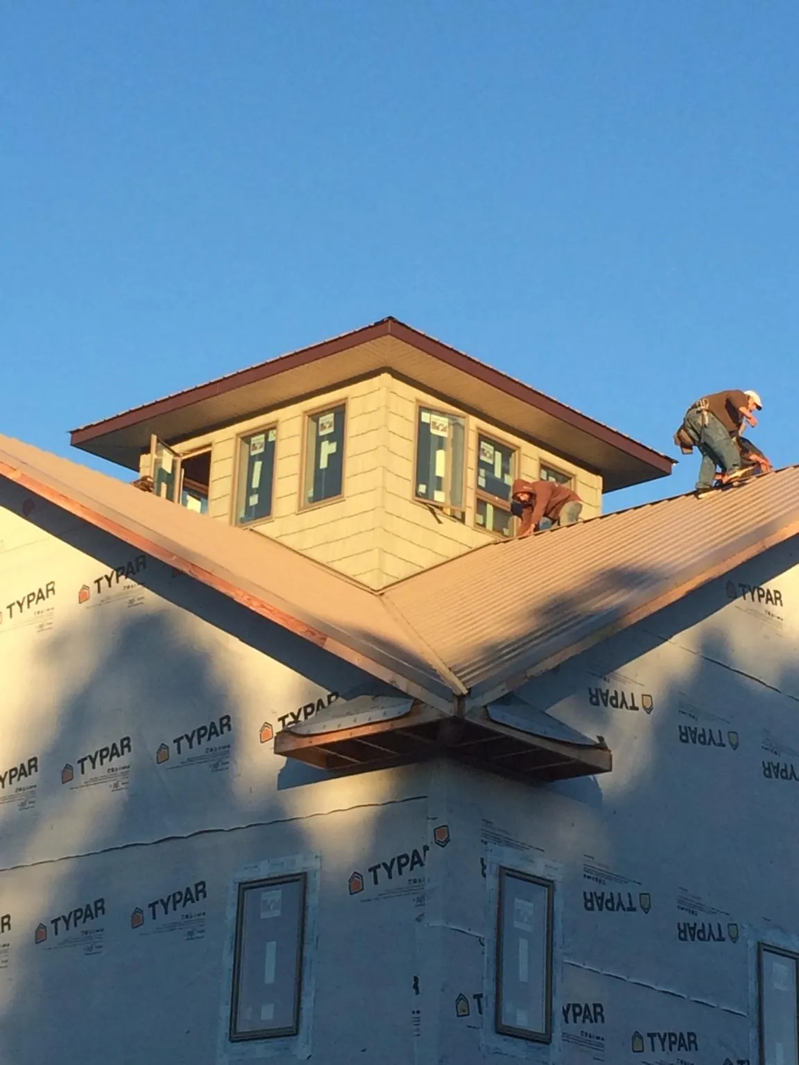 Roofers working around a rooftop cupola on a new metal roof at sunset — Roof Waterproofing in Conneautville by Roofing Brothers